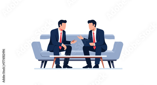 Two businessmen in suits having a casual but important discussion while sitting on a comfortable sofa in an office lounge.