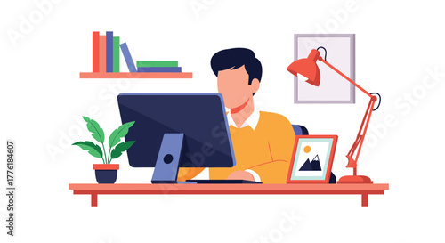 Man working on his computer at a well-organized home office desk with a plant, lamp, and picture frame creating a cozy atmosphere.