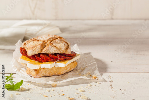 Ciabatta bread sandwich with brie cheese and a sausage made with pork and paprika.