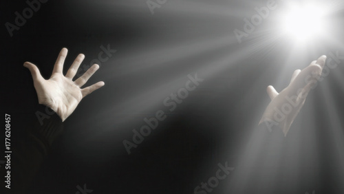 Silhouetted hands reaching toward divine light rays breaking through darkness. Dramatic spiritual imagery with strong contrast, powerful faith and hope concept. Religious and inspirational.
