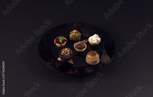 Assorted gourmet mini desserts on black plate