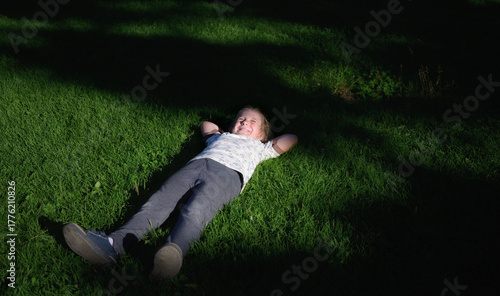 Child relaxing on grass in sunlight.