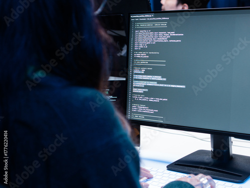 back view shot of Young Female computer programmer working on computer, writing code, developing app, Ai prompt project sit at desk in tech company office. Professional Programmer Working on Coding.