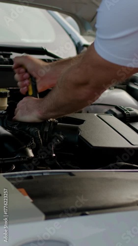 Mechanic inspecting vehicle performance data on laptop placed near engine, showcasing modern technology and automotive diagnostics in a professional garage environment