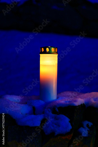 Solitary grave candle burning at the blue hour of the morning before sunrise on Christmas Day.  Vertical view. 