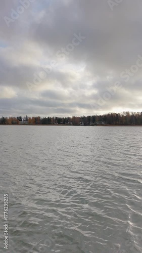 Fast drone flight just above calm water surface reflecting the sky