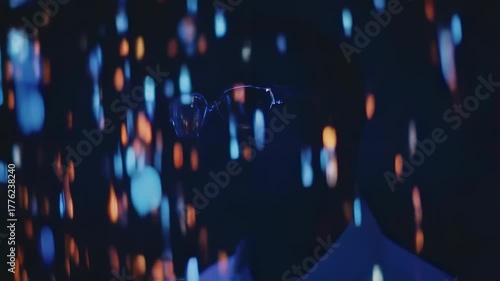 Abstract view of eyeglasses in a dark space with vibrant, out-of-focus lights