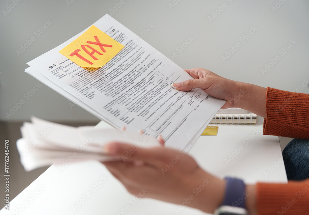 Obraz premium Tax filing. Individual holding tax documents and reviewing them at a desk.