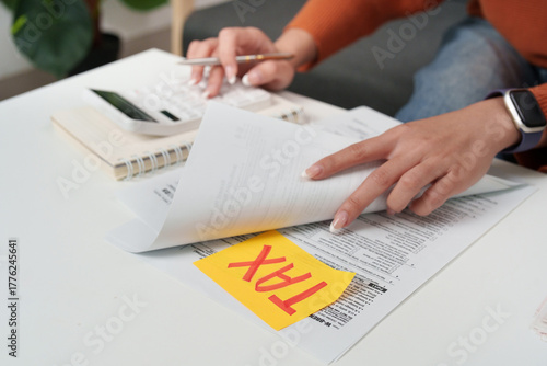Tax filing. Person reviewing tax documents and making calculations at home office.