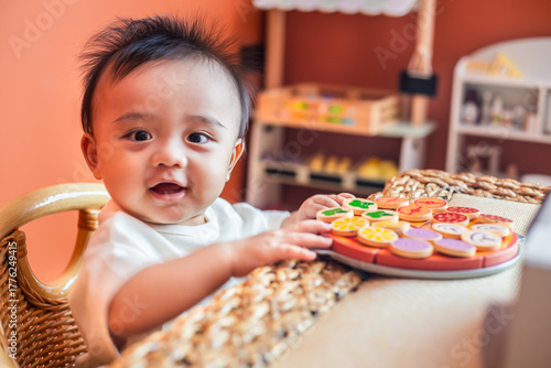 A cute little child smiles happily while playing with toys made from wood and non-toxic paint to enhance their development.