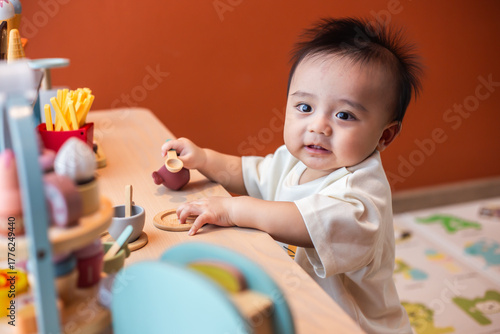 A cute little child smiles happily while playing with toys made from wood and non-toxic paint to enhance their development.