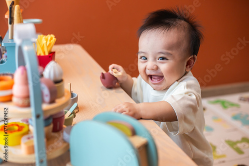 A cute little child smiles very happy while playing with toys made from wood and non-toxic paint to enhance their development.