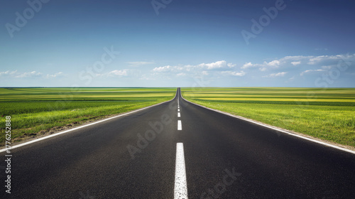 Straight empty road stretching to the horizon through green fields under a clear blue sky, symbolizing journey, freedom, travel, and endless possibilities.