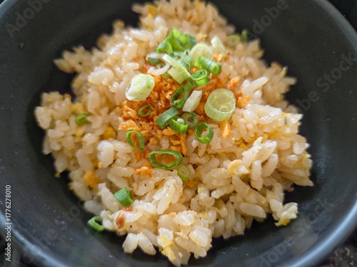 Close-up of a serving of garlic fried rice (likely Japanese or Asian style) in a dark bowl.