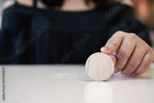 Photos Round wooden token placed on white table held by hand, minimal design for branding mockup, business planning, creative concept, and product identity