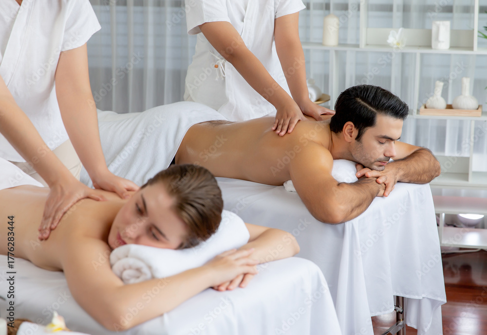 Fototapeta premium Caucasian couple customer enjoying relaxing anti-stress spa massage and pampering with beauty skin recreation leisure in day light ambient salon spa at luxury resort or hotel. Quiescent