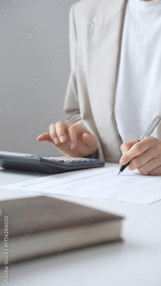 Fototapeta premium Professional businesswoman is calculating annual tax using calculator and taking notes in the office background, managing budget and checking financial documents. Audit and taxes in business