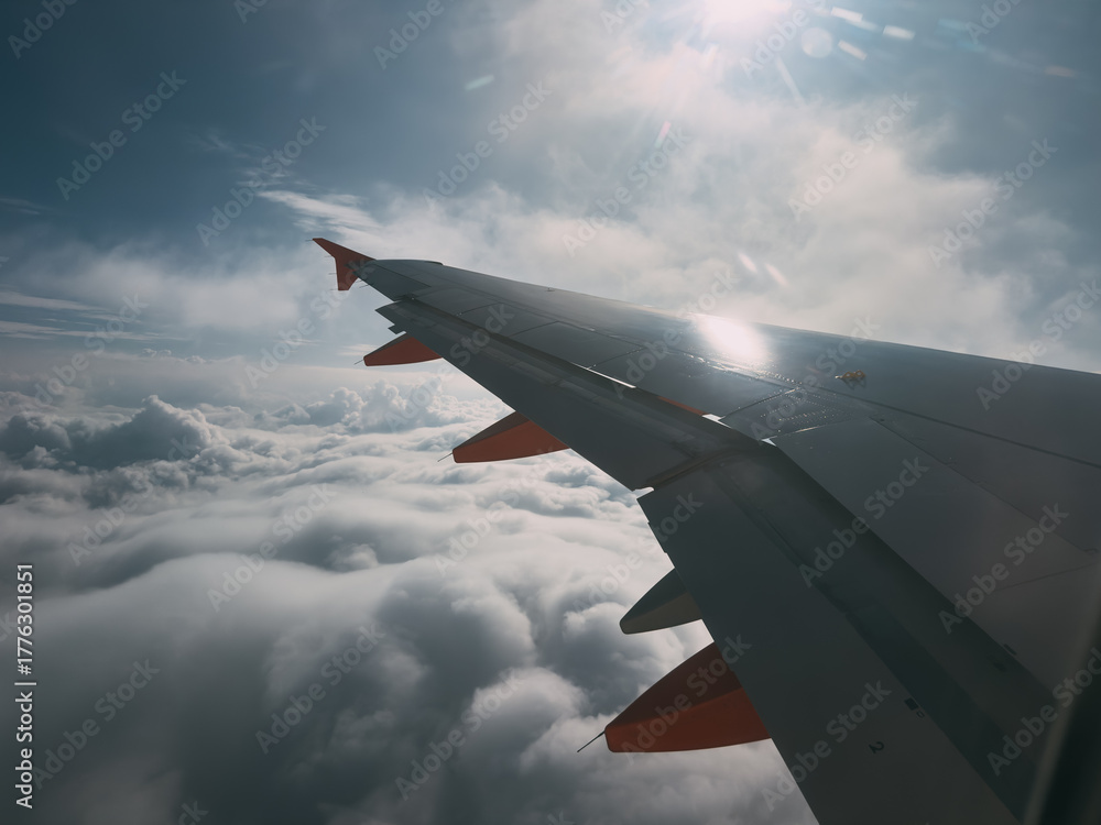 Obraz premium Airplane wing flying above clouds with sun rays