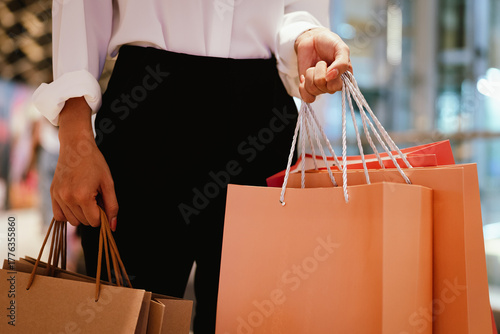 Close-up of a person holding multiple shopping bags in a mall, symbolizing retail therapy, consumerism, and modern lifestyle.