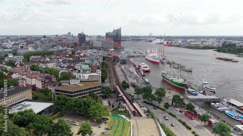 Aerial footage over Hamburg, Germany. Red U Bahn train is arriving at Baumwall station near Elbe river and harbor