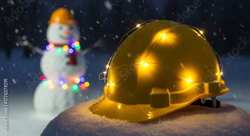 Yellow safety helmet with fairy lights on snow, winter construction holiday theme