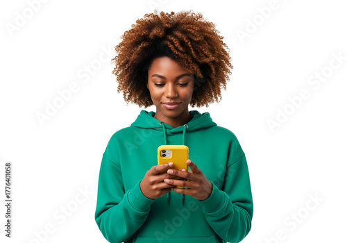 Happy African American woman in a green hoodie, looking at her yellow smartphone, portraying digital connectivity and mobile technology, isolated on transparent background.