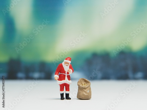 Mini toy of action figure at outdoor with blurred background. Miniature photography concept design. Minifigure of Santa claus character at snowland with gift bag. Snowman or snow doll at winter time.