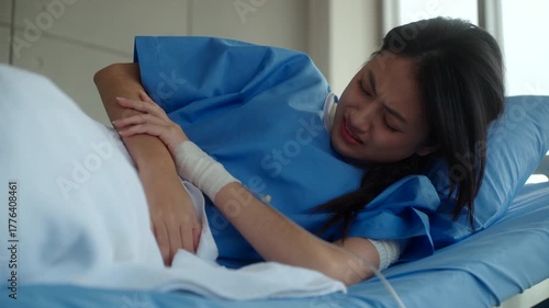 Woman patient sitting on hospital bed suffering stomach pain and diarrhea, feeling anxious about possible cancer and medical costs while waiting for diagnosis and treatment. Health insurance.
