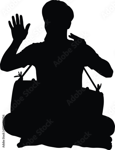 Silhouette of an Indian folk musician seated and playing a traditional percussion drum.