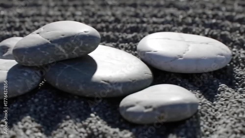 Smooth grey stones piled on textured sand background  
