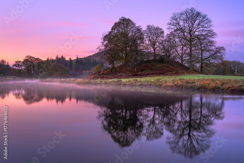 Pink and purple sunrise at The River Brathay with calm reflections, Lake District, UK.