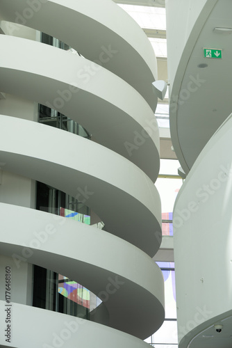Curved white staircases in a modern building with natural light filtering through a skylight.