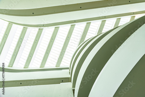 Curved modern architectural ceiling featuring lines and ample natural light through a skylight.