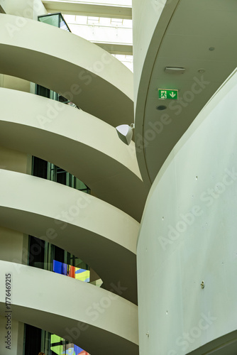 Curved architectural interior with white walls, modern design elements, and visible emergency exit sign.