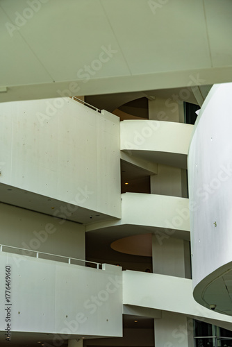 Curved white architectural interior with layered balconies and soft lighting in a modern building.
