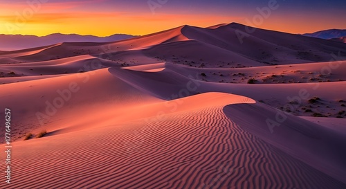 Majestic desert landscape with undulating sand dunes, vibrant sunset hues, and distant mountains creating a serene natural vista.