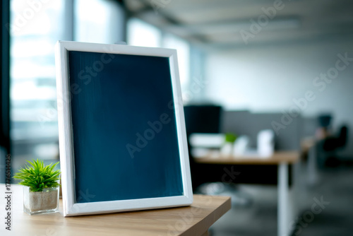 Wallpaper Mural A minimalistic office setting featuring a blank picture frame and a small potted plant on a desk, emphasizing a tidy workspace. Torontodigital.ca
