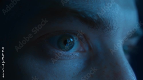 Close-up of a man wide-open eyes staring continuously at the screen in fear and astonishment. Addiction to social media, digital dependence and mindlessly doomscrolling 