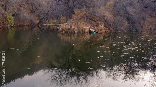A natural landscape in late autumn with a sunken iron boat in a lake