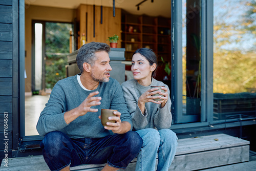 Foto Couple talking and enjoying coffee together on steps outside modern home, feelin