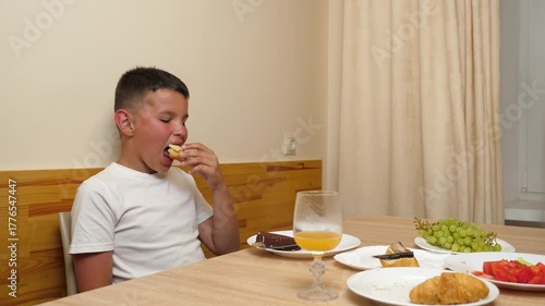 A boy is sitting at a table and eating ice cream for dessert.