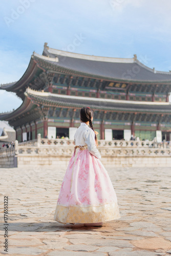 A woman dressed in traditional attire standing in front of a grand building