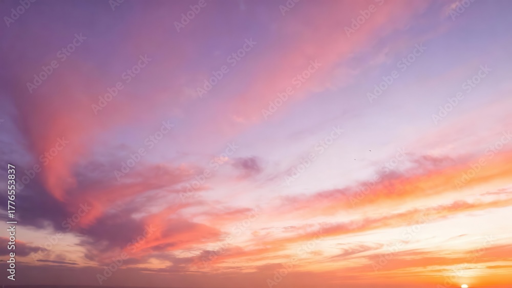 Fototapeta premium Wispy clouds paint the sky with vibrant sunset hues of pink and purple.