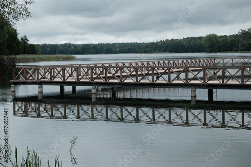 Fototapeta Naklejka Na Ścianę i Meble -  Drewniane molo na jeziorze Ołów, Mazury, spokojna woda i odbicie pomostu w jeziorze