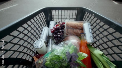 POV 4K Ultra HD footage of hands putting food and drinks into a grocery store shopping cart, showing retail consumer lifestyle, supermarket shopping, and daily purchase activity.