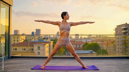 Young woman practicing yoga in Warrior pose on balcony at sunset  