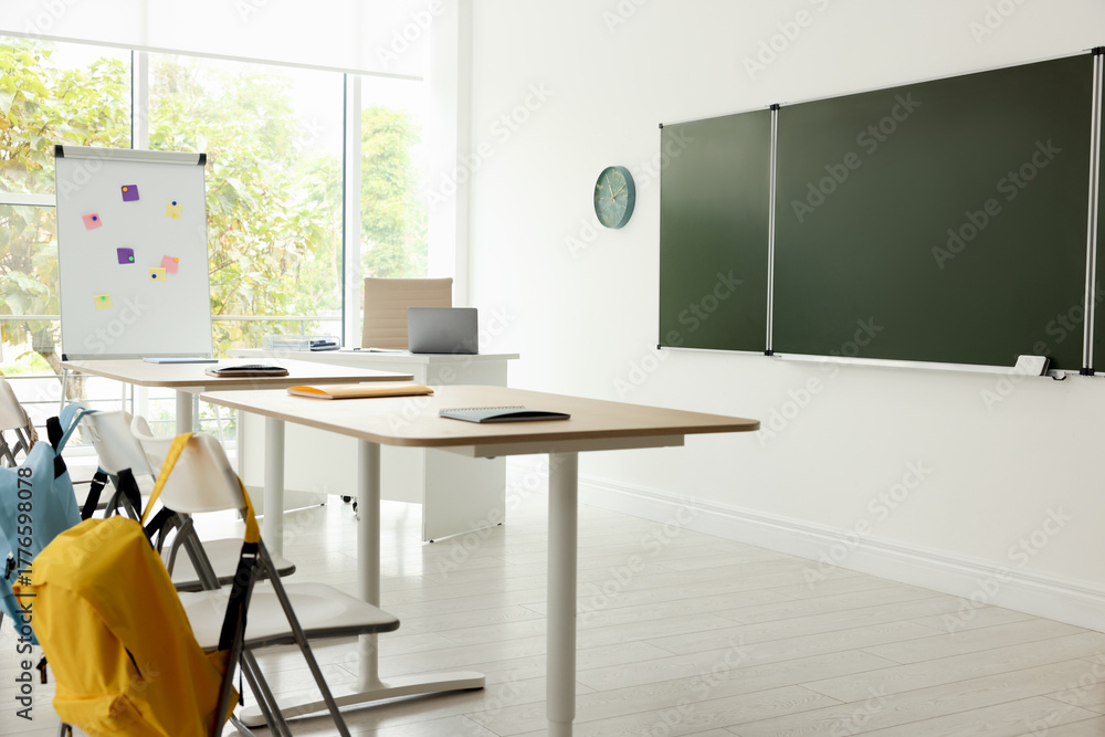 Fototapeta premium Green chalkboard and stylish furniture in classroom. Mockup for design