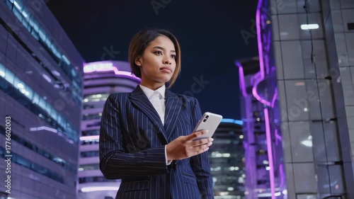 Wallpaper Mural confident businesswoman holding smartphone at night in a futuristic city, surrounded by glowing neon lights and digital billboards Torontodigital.ca
