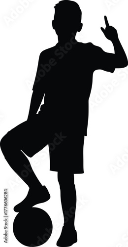 Silhouette of a young boy standing with a soccer ball and holding up two fingers in a victory sign
