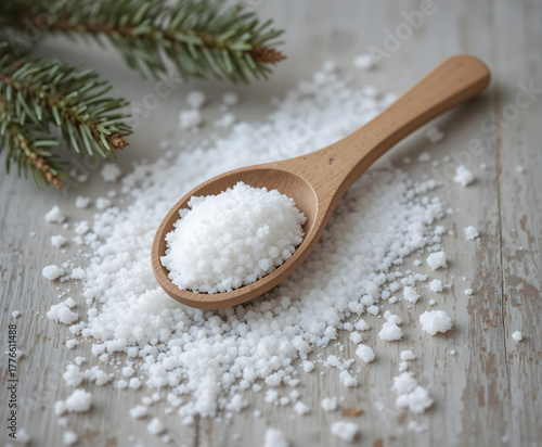 Wooden spoon filled with coarse salt on a rustic table with pine branch decoration